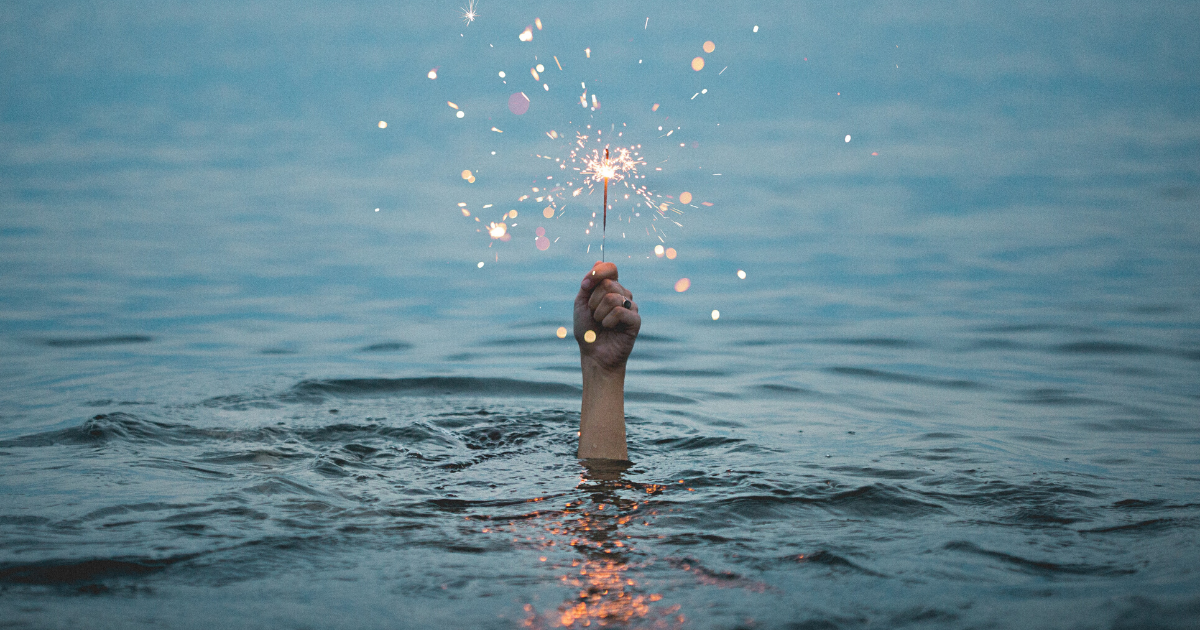 hand holding sparkler coming out of the water