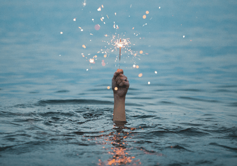 hand holding sparkler coming out of the water